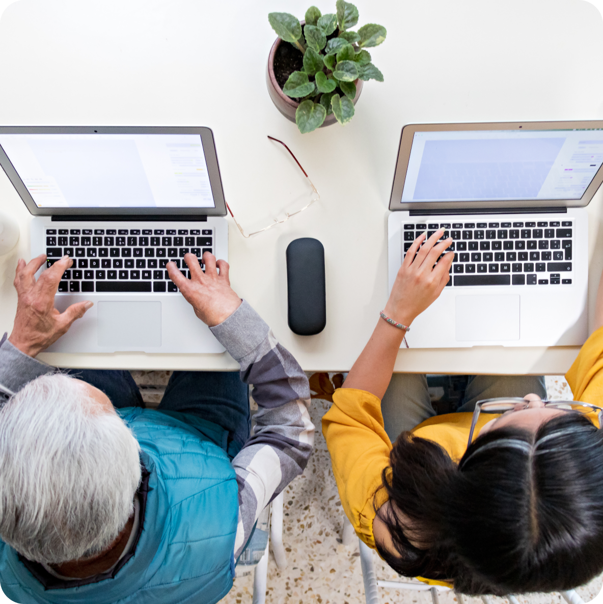 a man and a woman are typing on their laptops