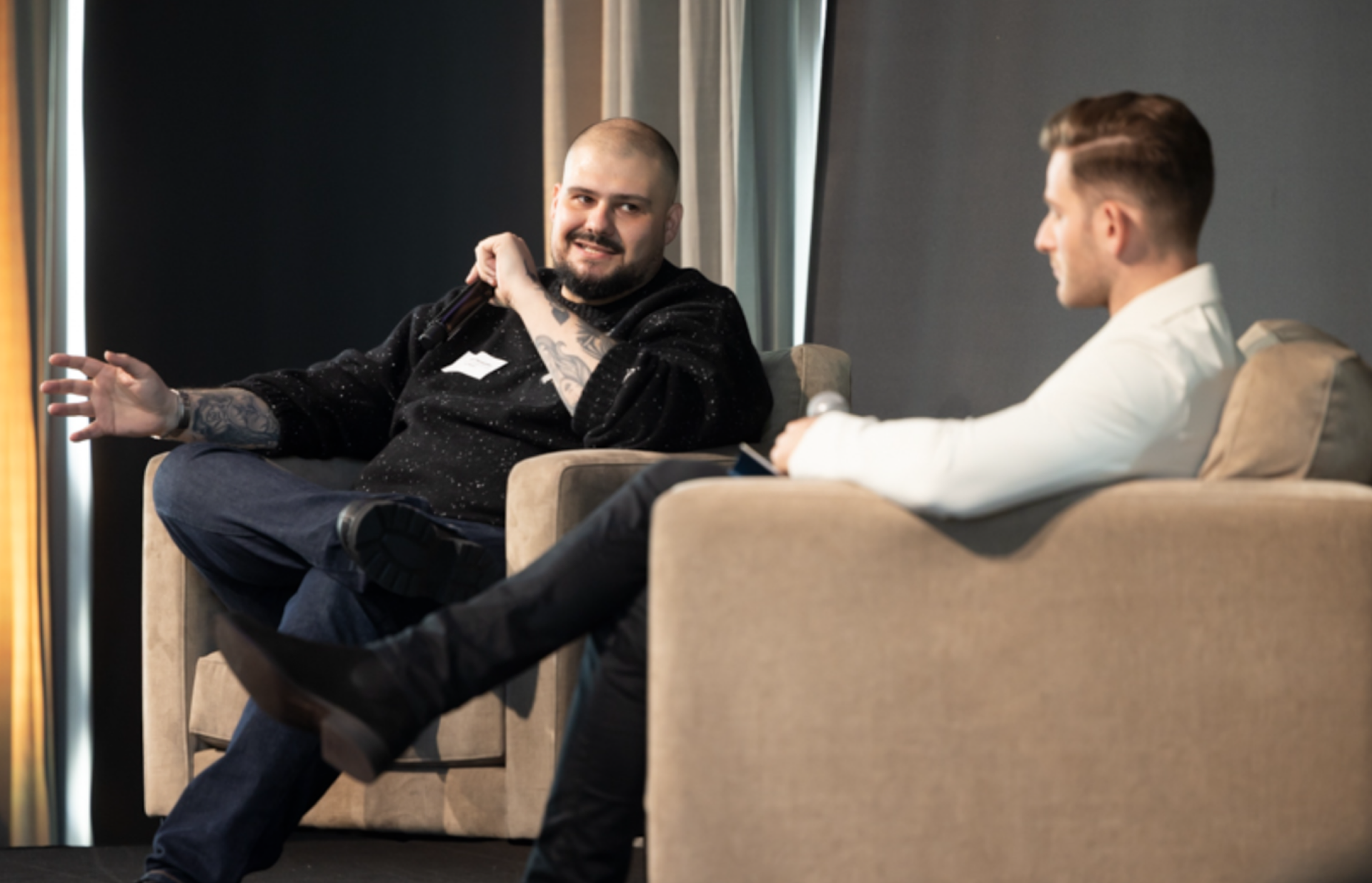 a man with a name tag on his shirt sits next to another man