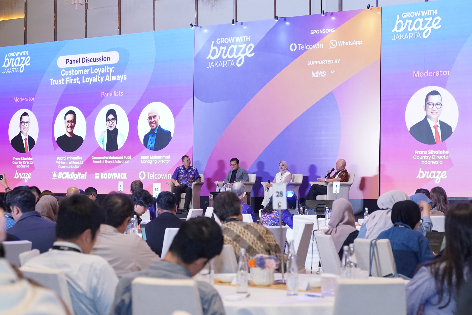 Panelists discuss customer loyalty onstage at the Grow With Braze Jakarta event as attendees watch from banquet tables.