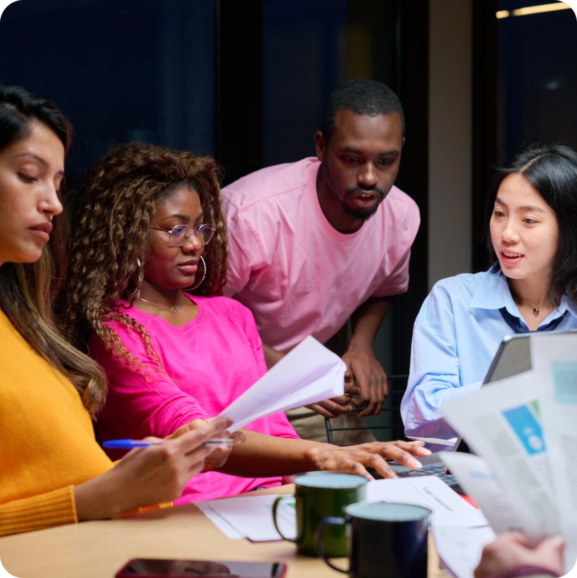 a group of people are sitting around a table looking at papers