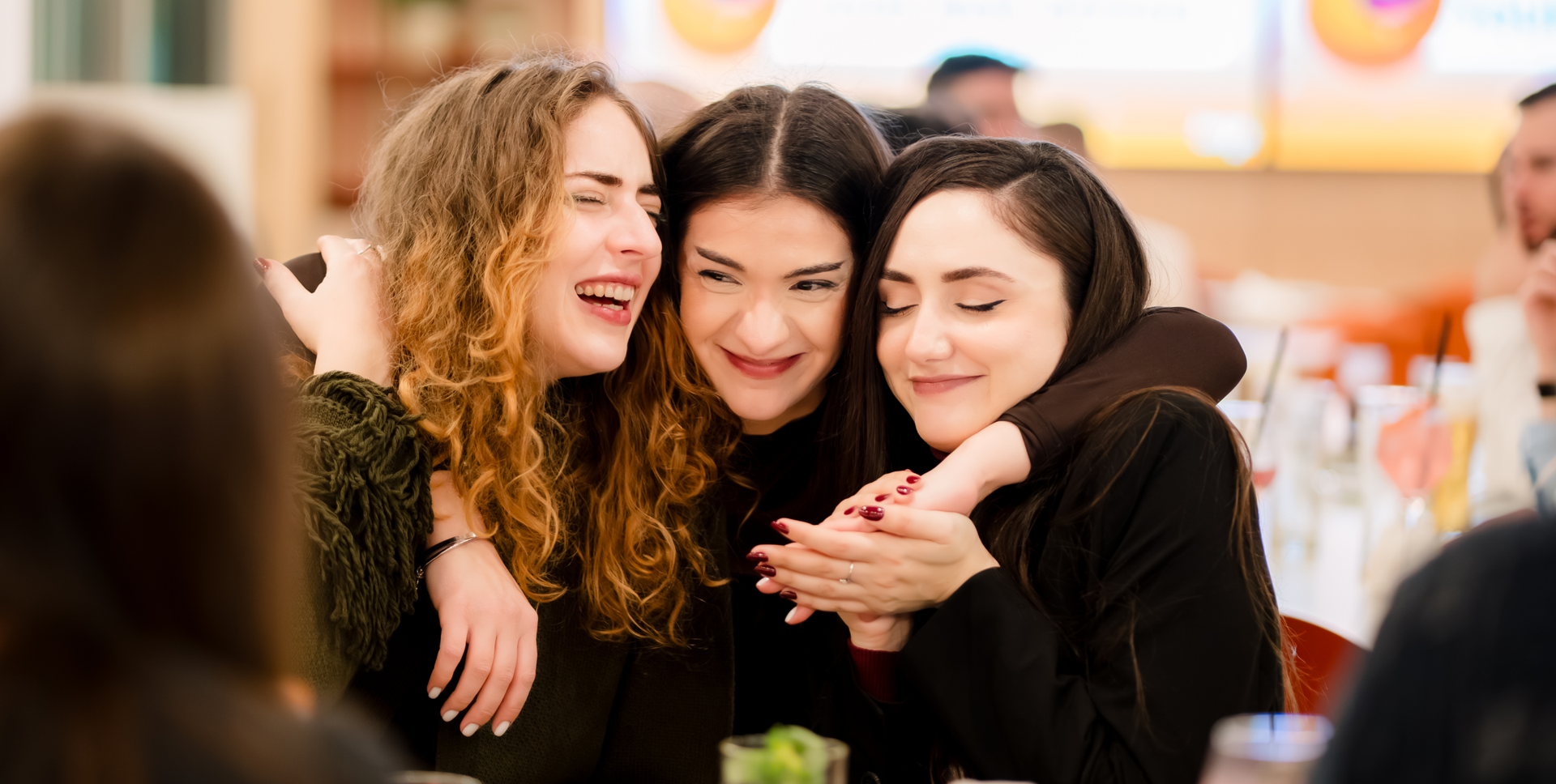 Three women embracing and laughing together.