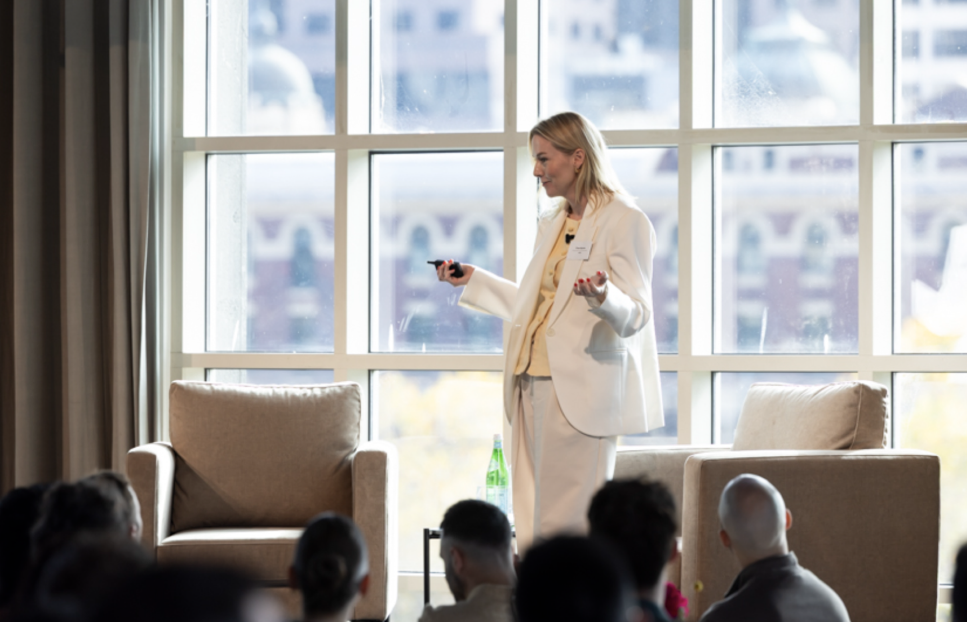a woman in a white suit is giving a presentation